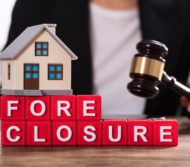 Foreclosure concept with toy house and lawyer with gavel.